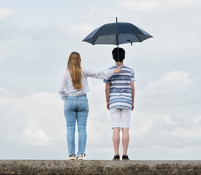 Women protecting boy from rain